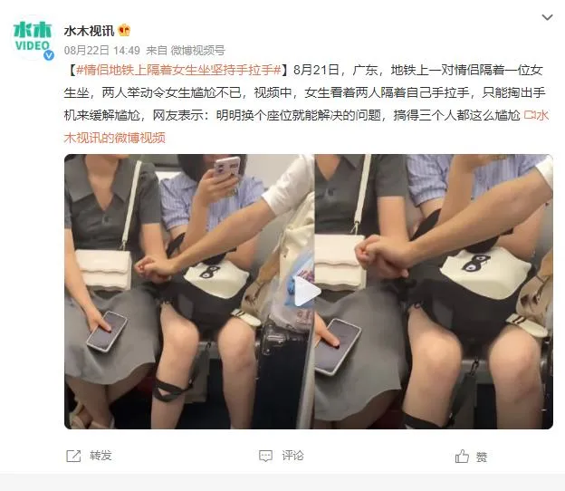 情侣地铁上隔人坐仍手拉手 中间女生玩手机缓解尴尬